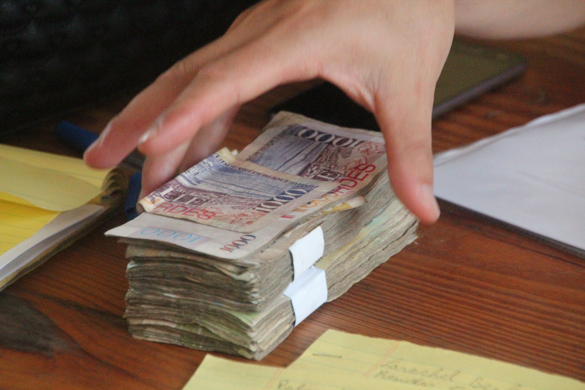 A hand grabing Haitian bills on a table